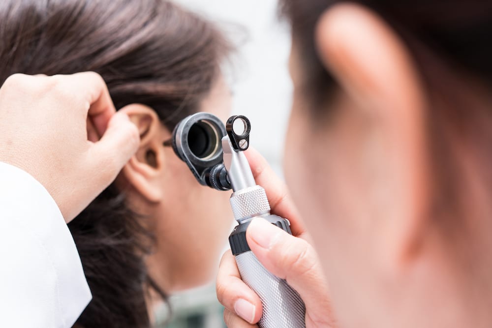 Audiologist looking into patients ear